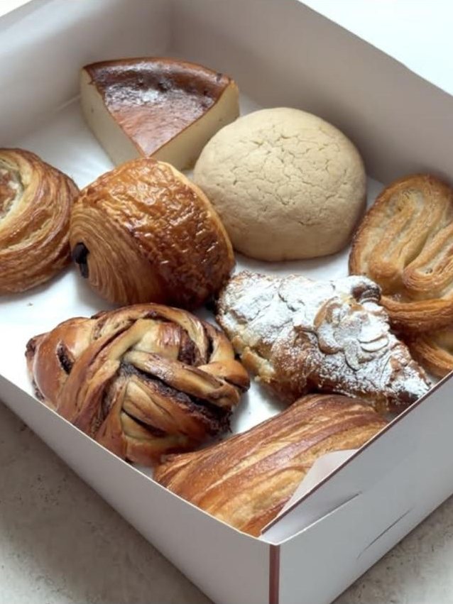 Caja de pan MOMI con tarta vasca, concha, pain au chocolat, palmera y croissant de almendra